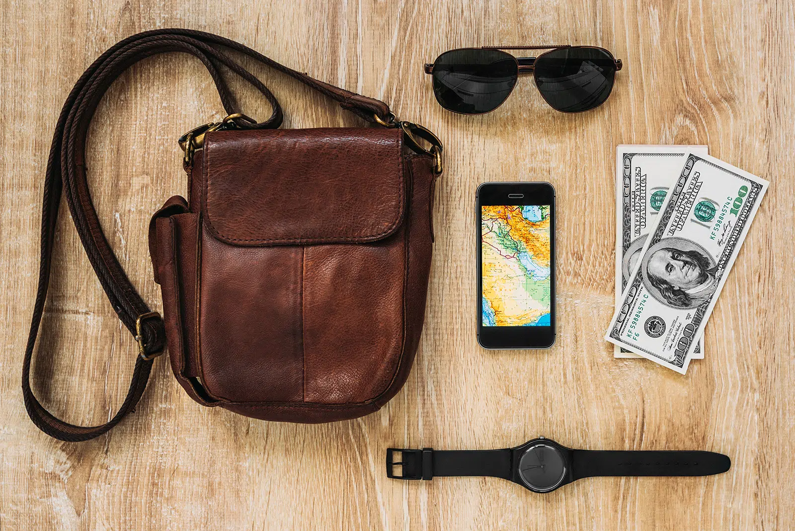 Leather bag, smartphone, sunglasses, watch, money on wooden background. Men's accessories